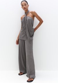 Gray two-piece outfit featuring a halter top with draped fabric and loose, wide-leg trousers, made from a textured material.