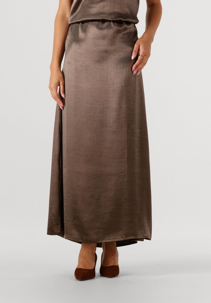 Bruine satijnen maxi rok met een soepele textuur en een zijsplit, gedragen met bruine pumps. De tailleband is gerimpeld voor een goede pasvorm.