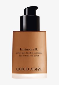 Bouteille en verre brun avec un capuchon noir à pompe, étiquetée "Luminous Silk" fond de teint de Giorgio Armani dans une typographie élégante.
