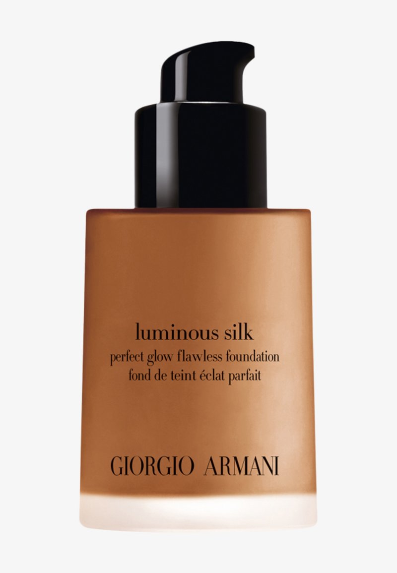 Bouteille en verre brun avec un capuchon noir à pompe, étiquetée "Luminous Silk" fond de teint de Giorgio Armani dans une typographie élégante.