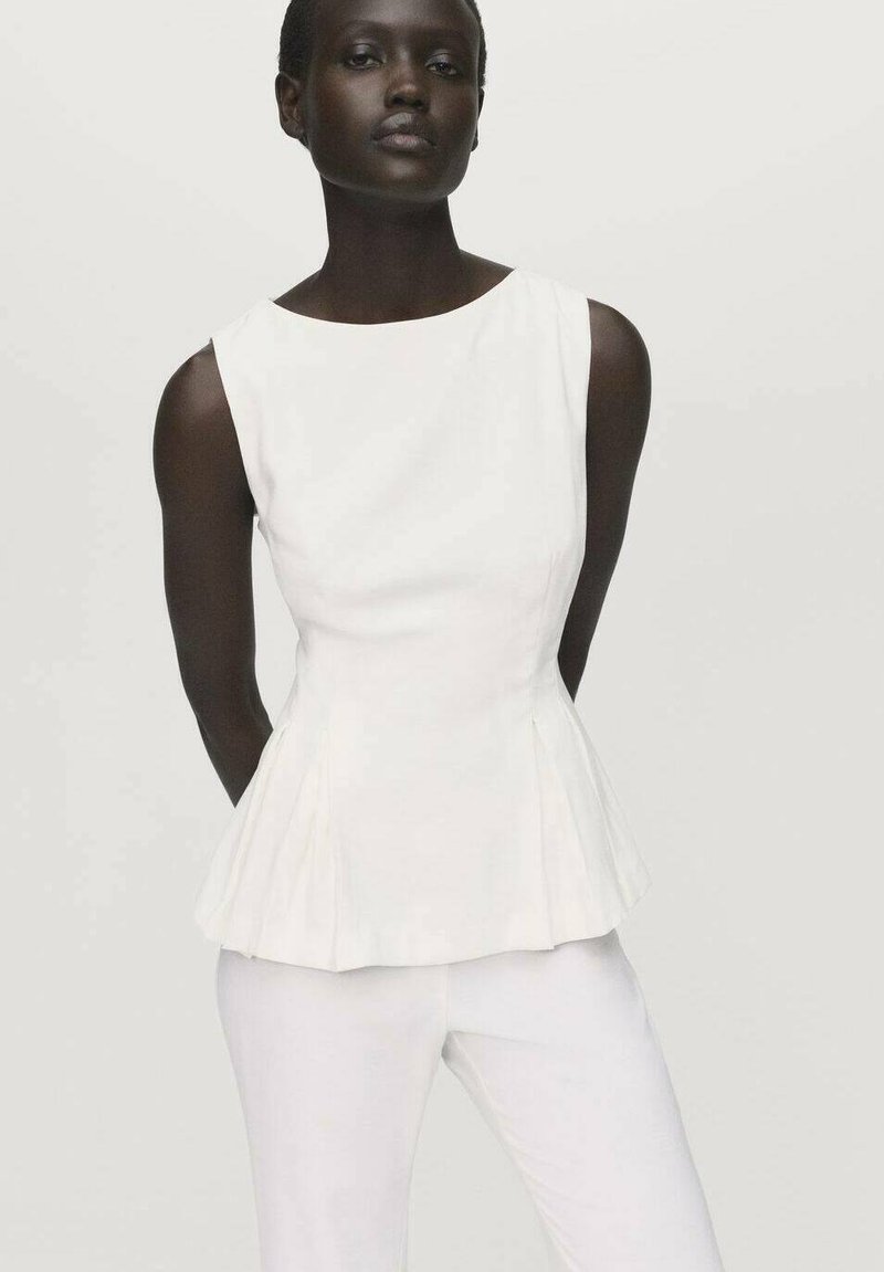 Top peplum bianco con scollatura rotonda, caratterizzato da pieghe strutturate e una texture liscia, abbinato a pantaloni bianchi aderenti.