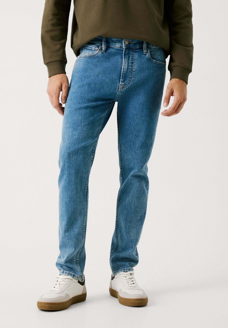 Lys blå denimjeans med rett snitt, fem lommer og en lett falmet tekstur, kombinert med hvite joggesko.