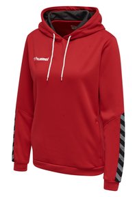 Rood hoodie van een geweven stof, met witte trekkoordjes en zwart-wit chevronaccenten op de mouwen. Heeft een logo op de borst.