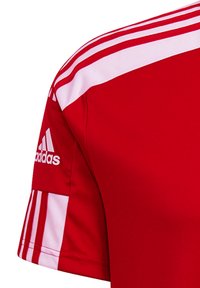 Rode atletiektrui met witte zijkanten, gemaakt van synthetische stof. Bevat het Adidas-logo op de mouw. Korte mouwen.