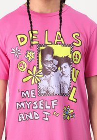 Pink cotton t-shirt featuring bold graphics, including "DE LA SOUL" and a black-and-white photo with colorful floral designs and text.