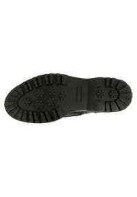 Suela de zapato de goma negra con bandas profundas, que presenta patrones circulares y en forma de estrella para tracción y estabilidad. Diseño de perfil plano.
