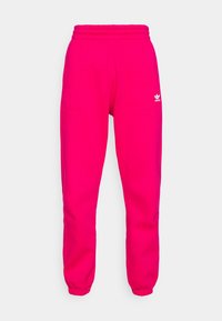 Růžové tepláky s elastickým pasem, zúženými nohavicemi, bočními kapsami a bílým logem Adidas na levém stehně. Hladký materiál.
