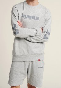 Felpa grigia con logo "HUMMEL", polsini a costine e pantaloni corti abbinati, con logo stampato e righe laterali a contrasto.
