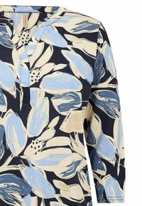 Floral tuniek met een marineblauwe basis, met lichte blauwe en beige bladvormen. Zachte stof met een V-hals en driekwart mouwen.