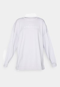 Sweatshirt blanc surdimensionné avec des manches longues, un col rond et le texte imprimé "ATHLEISURE" en gris subtil sur la poitrine. Texture de tissu douce.