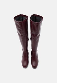 Μπορντό δερμάτινες μπότες μέχρι το γόνατο με απαλή υφή, στρογγυλεμένη μύτη, πλαϊνά φερμουάρ και εφαρμοστή σχεδίαση.