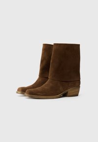 Bottes de cheville en daim marron avec un revers plié, un bout arrondi et un petit talon en bois. Texture lisse et design simple, adapté à diverses occasions.