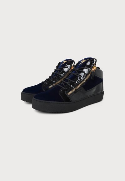 Ζευγάρι μαύρα sneakers με ψηλό πέλμα, χρυσά πλαϊνά φερμουάρ, μαύρα κορδόνια και γυαλιστερό φινίρισμα στα πάνω μέρη και στη σόλα.