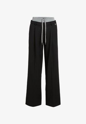 Schwarze weit geschnittene Hose mit einem grauen elastischen Bund und langen grauen Kordeln, ausgestattet mit Gürtelschlaufen und einer kleinen metallischen Verzierung.