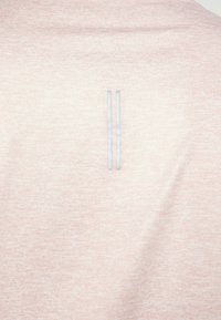 Světle růžové sportovní tričko s jemnou texturou, vybavené dvěma paralelními světle modrými pruhy na zádech. Jednoduchý design a přiléhavý střih.