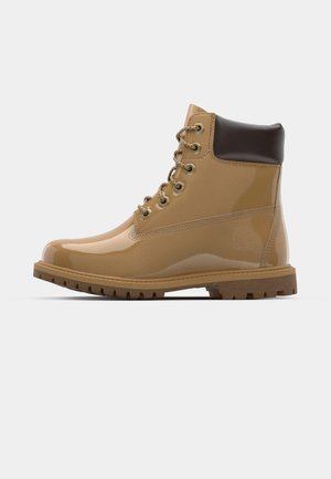 Botas de tobillo de charol color naranja con acentos marrones, puntera redonda, seis ojales metálicos, cordones marrones y suela de goma texturizada.