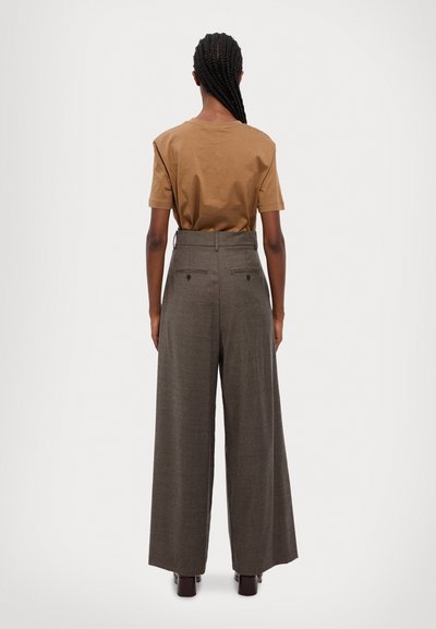 Camiseta de algodón marrón de manga corta, combinada con pantalones de cuadros gris de tiro alto y pierna ancha, que cuentan con bolsillos traseros.