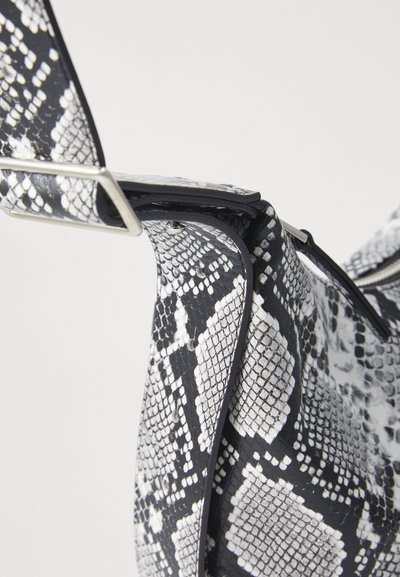 Sac à main en imprimé python noir et blanc avec une texture lisse, une forme flexible et un accent en métal argenté en haut.