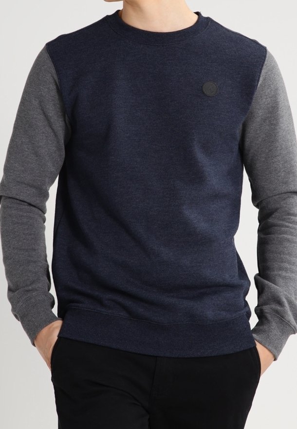 Bluza z okrągłym dekoltem w granatowym kolorze z szarymi rękawami, wykonana z miękkiego materiału o teksturowanym wykończeniu, z małym czarnym logo na piersi.