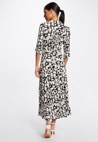 Schwarz-weiß gemustertes Kleid mit Dreiviertelärmeln, tailliertem Design und fließender Maxi-Länge, das eine lockere Passform und leichten Stoff bietet.