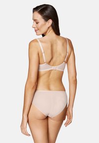 Jasnoróżowy zestaw bielizny z gładkiego, elastycznego materiału. Biustonosz ma regulowane ramiączka i zapięcie na haczyk, a do kompletu pasują wysokie majtki.