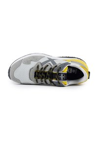 Scarpa sportiva grigia e gialla con tomaia in rete, sovrapposizioni in camoscio e lacci giallo e nero con macchie. Presenta una suola in gomma per aderenza.