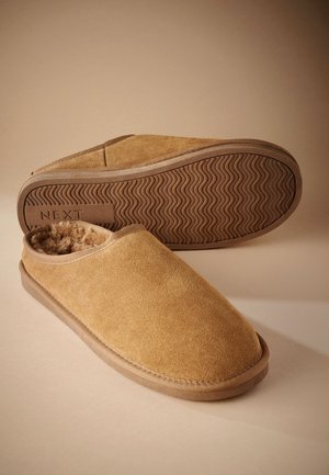 Braune Wildleder-Hausschuhe zum Hineinschlüpfen mit weichem Fleecefutter und profilierter Gummisohle, ein Hausschuh zeigt die Sohle mit der "NEXT"-Markierung.