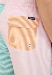 Gestreepte shorts in pastel roze, groen en oranje kleuren. Inclusief een oranje gestreepte zak met een drukknop en ogen detail.