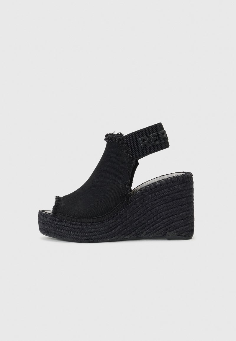 Sandales compensées noires avec un dessus en tissu et une sangle de cheville élastique, dotées d'une semelle en jute texturé et de détails à bords effilochés.