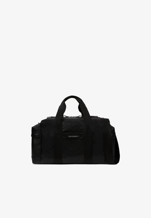 Sac polochon noir avec motif en relief, doubles poignées supérieures, bandoulière réglable et une étiquette frontale indiquant "Karl Lagerfeld."