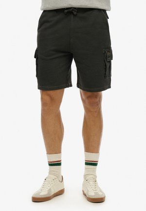 Pantaloni cargo grigio scuro in cotone misto, con vita regolabile e tasche laterali. Abbinati a sneaker bianche e calze a righe.