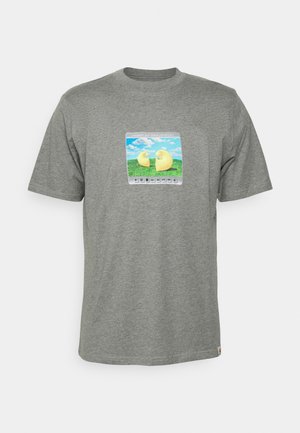 Szara koszulka z krótkim rękawem z kwadratowym nadrukiem przedstawiającym dwa żółte abstrakcyjne kształty na zielonej trawie pod niebieskim niebem, przypominającym interfejs odtwarzacza multimedialnego.