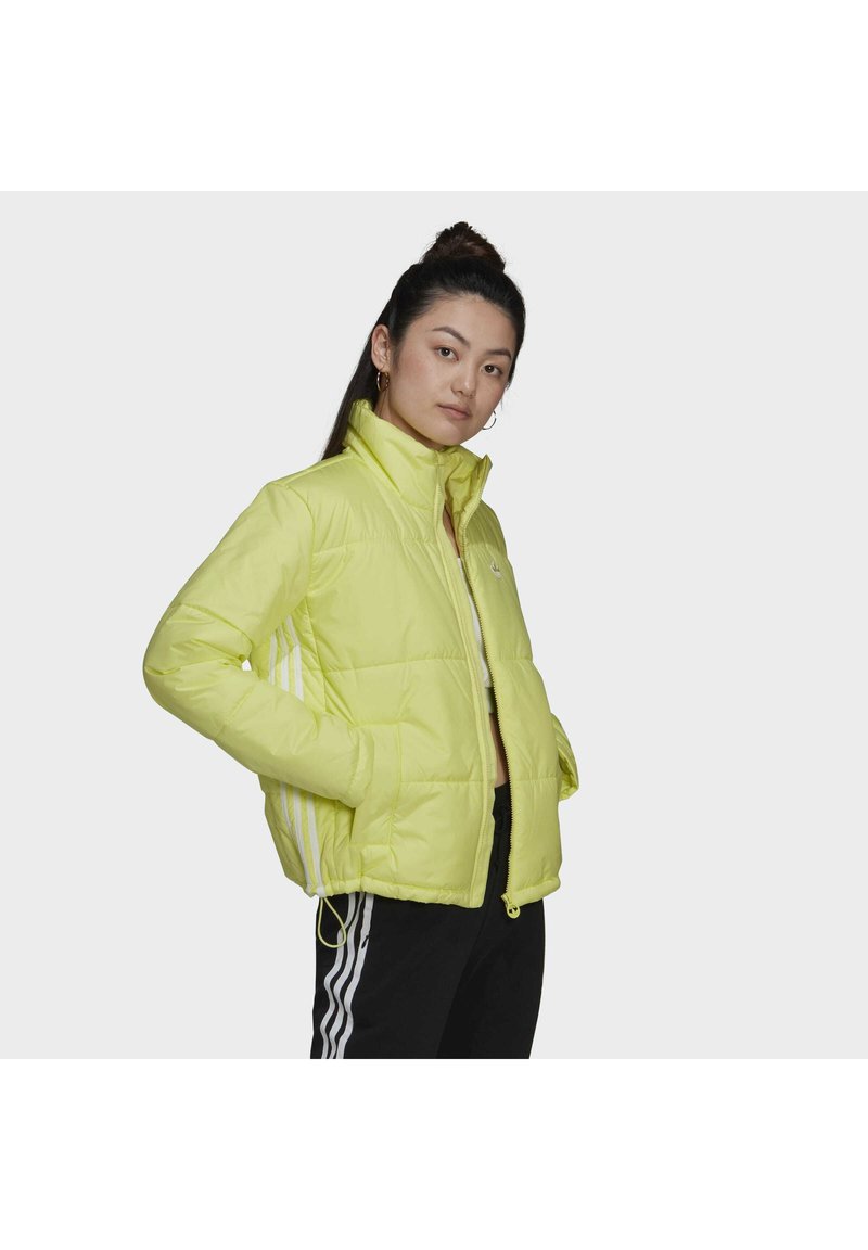 Gul puffjacka med hög krage, dragkedja, sidofickor och vita randig detaljer på ärmarna. Slät, glänsande material.