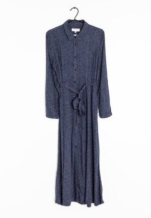 Robe boutonnière à manches longues bleu marine avec de petits pois blancs, col et ceinture à la taille, suspendue à un cintre noir.