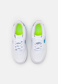 Białe sneakersy Nike z niebieskimi akcentami i zieloną wkładką. Posiadają teksturowaną cholewkę oraz perforacje dla lepszej wentylacji. Sznurówki są białe.