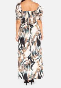 Maxi sukienka z kwadratowym dekoltem, bufkami i marszczonym korpusem. Materiał ma odważny, abstrakcyjny wzór liści w neutralnych odcieniach.