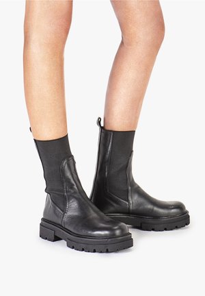 Schwarze Leder-Stiefeletten mit elastischen seitlichen Einsätzen, dickem Gummisohle und einer Schlaufe hinten für einfaches Anziehen.