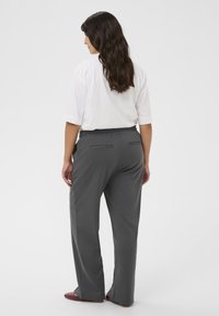 Grijze ontspannen passende broek met een elastische tailleband, voorzien van zijzakken en een gladde textuur, gecombineerd met een wit T-shirt met korte mouwen.