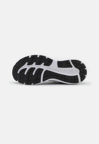 Semelle en caoutchouc noir avec un motif texturé et des rainures, dotée d'une semelle intermédiaire blanche. Conçue pour l'adhérence et le soutien dans des chaussures de sport.