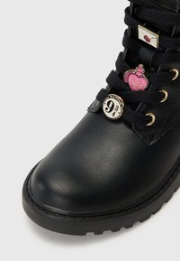 Bottine en cuir noir avec semelle en caoutchouc épaisse, ornée de broches décoratives : une potion d'amour rose, une enveloppe et un badge "Plateforme 9¾".
