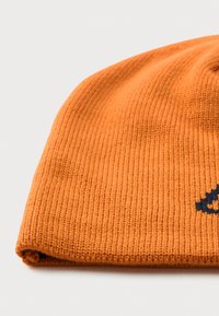 Orange strikket hue med ribbete tekstur, foldet kant og delvist lille sort broderet design synligt på lys baggrund.