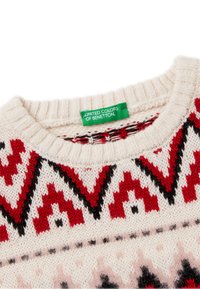 Sweter z dzianiny o kremowej bazie, z czerwonymi i czarnymi geometrycznymi wzorami. Żebrowany kołnierz oraz tkana metka marki w kolorze zielonym.