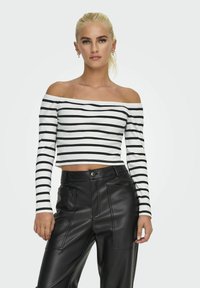 Czarna i biała, paskowana, odkryta ramiona bluzka crop top z prążkowanej tkaniny, zestawiona z czarnymi spodniami z ekoskóry o wysokim stanie z przednimi kieszeniami.
