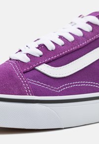 Fioletowe zamszowe sneakersy z białymi sznurówkami. Posiadają białe skórzane akcenty i czarny pasek na podeszwie, z widocznymi szczegółami szycia.