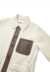Beige gewatteerde jas met een bruin leren zak en kraag. Voorzien van een knoopsluiting en een gestructureerde stof. Toont een logo op de zak.