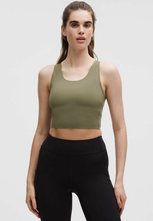 Olivově zelený crop top z hladkého, elastického materiálu s širokými ramínky a zaobleným výstřihem, který je spárován s černými legínami s vysokým pasem.