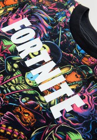 Fekete póló színes grafikával a Fortnite karaktereivel; nagy fehér "FORTNITE" felirattal az elején; pamut anyag.