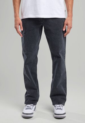Dark gray denim jeans with a relaxed fit, straight leg design, and subtle fading; paired with white sneakers.