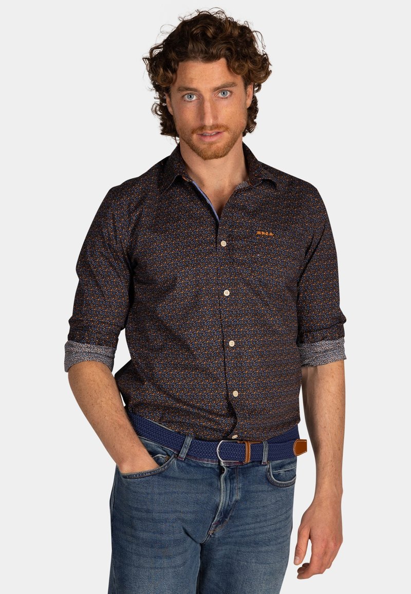 Heren overhemd met knoopjes in donker marineblauw met een gepatroneerd ontwerp, voorzien van een kraag, opgerolde manchetten en een geborduurd logo. Gecombineerd met blauwe jeans.