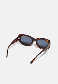 Óculos de sol em padrão tartaruga com um design elegante e angular, lentes escuras e laterais finas com padrões em laranja e castanho.
